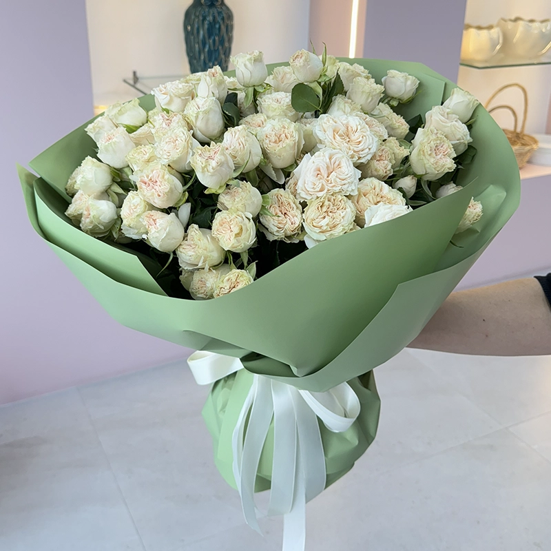 Elegant hand-tied bouquet of white roses, beautifully wrapped in paper, a luxury floral gift available for delivery in the UAE.